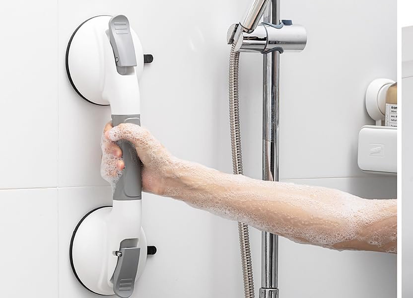 A hand gripping a TAILI suction shower grab bar mounted on a tiled shower wall